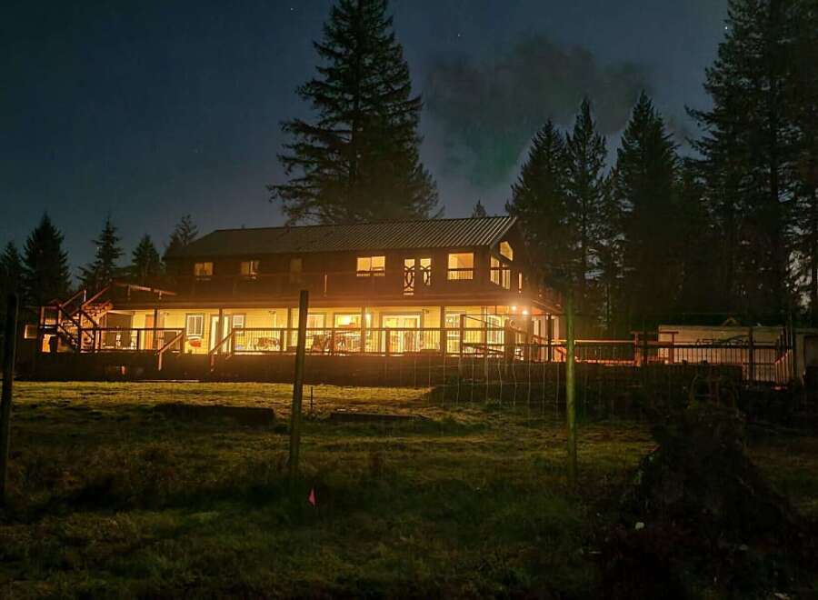 Experience the charm of this expansive home, illuminated by warm interior lights against the night sky.