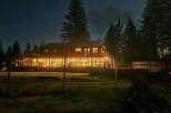 Experience the charm of this expansive home, illuminated by warm interior lights against the night sky.
