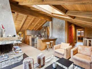 Experience rustic luxury in this stunning mountain chalet featuring a grand stone fireplace and exposed wooden beams.