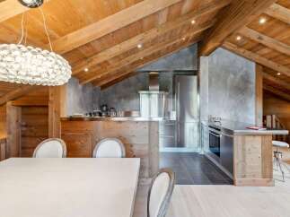 Experience luxury mountain living in this stunning chalet-style kitchen, featuring a vaulted wooden beam ceiling and a modern stainless steel appliance suite.