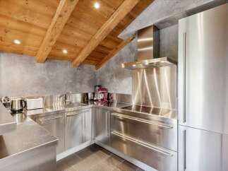 Experience modern luxury in this stunning kitchen, featuring sleek stainless steel countertops and appliances that gleam under the warm glow of recessed lighting.