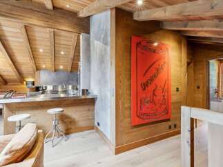 Experience luxury mountain living in this stunning chalet, featuring a modern kitchen with a sleek stainless steel island and bar stools.