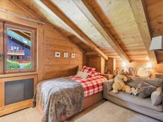 Experience cozy living in this charming attic bedroom, featuring exposed wooden beams and a rustic aesthetic.