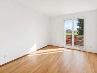 Experience bright and airy living in this unfurnished room, featuring a pristine white finish and a beautiful wooden floor that catches the sunlight.