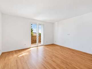 Step into this bright and airy room, featuring gleaming hardwood floors that reflect the natural light streaming in from the large sliding glass doors.