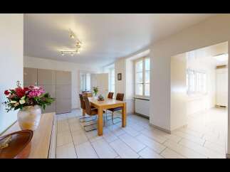 This spacious dining area features a modern wooden dining table with four comfortable brown leather chairs, perfect for family meals.
