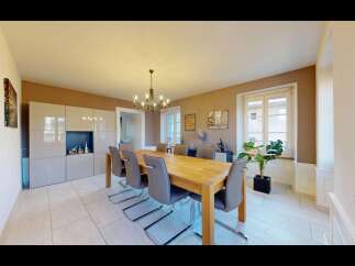 This elegant dining room features a spacious wooden dining table with eight grey upholstered chairs, perfect for hosting gatherings.