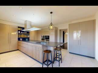 Experience modern luxury in this stunning kitchen, featuring sleek, high-gloss cabinetry and a spacious island with a built-in sink.