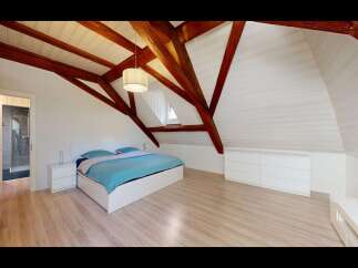Experience the charm of this attic bedroom, featuring exposed wooden beams that add rustic character to the vaulted ceiling.