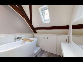Experience luxurious relaxation in this stunning attic bathroom, featuring a freestanding soaking tub with a convenient bath tray.