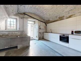 Discover this unique kitchen featuring a rustic, vaulted stone ceiling and exposed pipes, adding industrial charm.