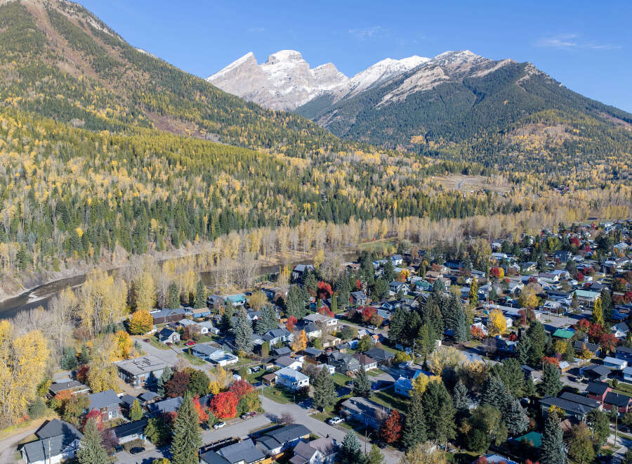 Experience the beauty of autumn in this charming mountain town, nestled beside a serene river and surrounded by majestic, snow-capped peaks.