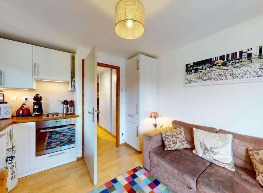 This charming apartment features a modern, well-equipped kitchen with white cabinetry, a microwave, and an oven, perfect for preparing meals.