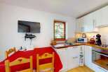 This charming kitchen features a cozy dining area with a red tablecloth and wooden chairs, perfect for intimate meals.