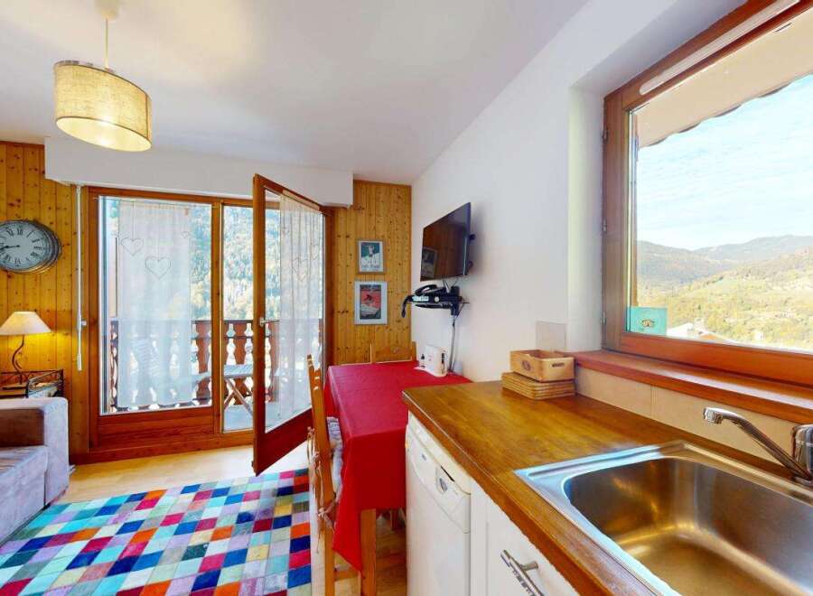This charming apartment features a cozy living area with a comfortable sofa and a colorful diamond-patterned rug, perfect for relaxing after a day of skiing.