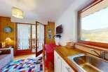 This charming apartment features a cozy living area with a comfortable sofa and a colorful diamond-patterned rug, perfect for relaxing after a day of skiing.