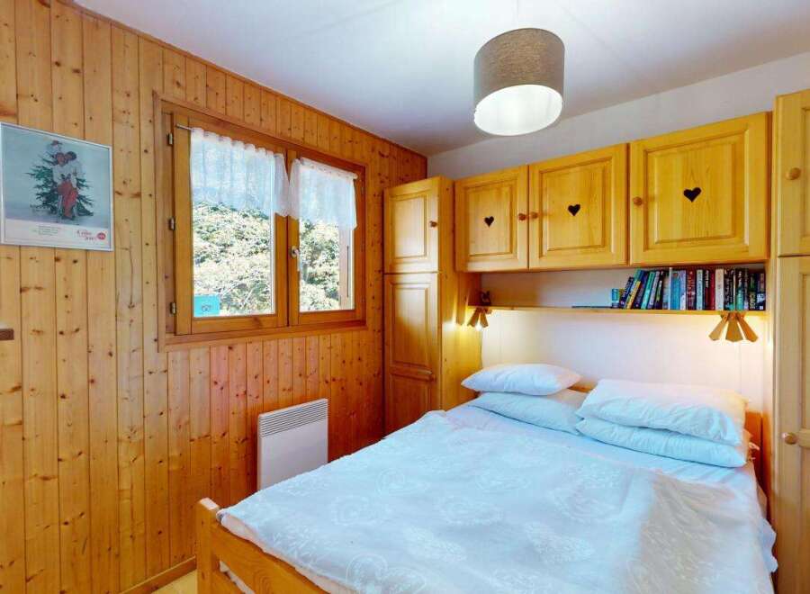 This charming bedroom features warm wood paneling throughout, creating a cozy and inviting atmosphere.