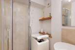 This modern bathroom features a convenient washing machine next to a sleek glass-enclosed shower.