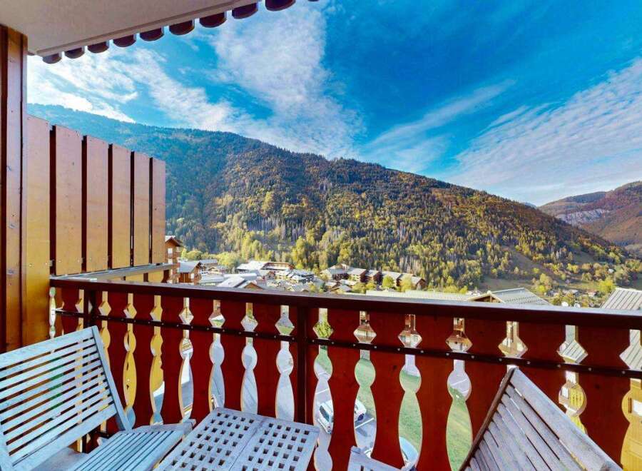 Enjoy breathtaking mountain views from this charming balcony, complete with a wooden table and chairs.