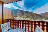 Enjoy breathtaking mountain views from this charming balcony, complete with a wooden table and chairs.
