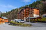 Experience mountain living in this charming wooden apartment building, nestled against a backdrop of lush pine forests and snow-capped peaks.