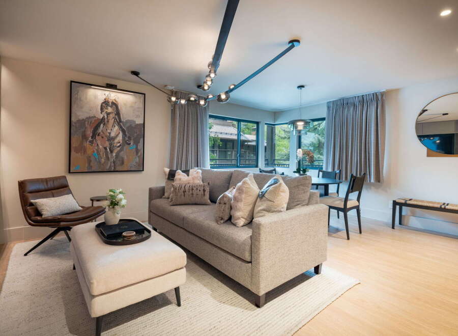 Experience modern living in this beautifully appointed living space, featuring a plush sectional sofa adorned with decorative pillows and a stylish leather accent chair.