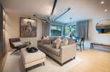 Experience modern living in this beautifully appointed living space, featuring a plush sectional sofa adorned with decorative pillows and a stylish leather accent chair.