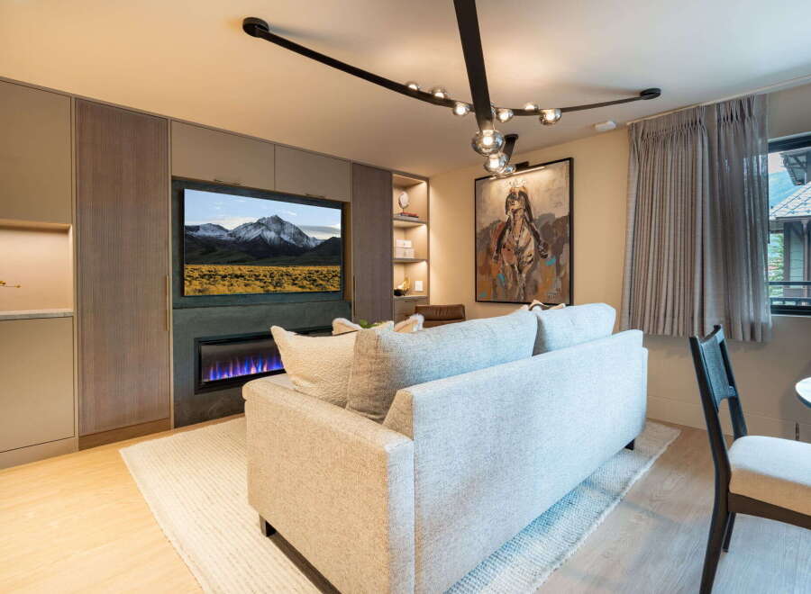 Experience modern living in this stylish living room, featuring a sleek fireplace and a large flat-screen TV mounted above it.