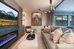 Experience luxury living in this stunning living room, featuring a modern fireplace with vibrant blue flames and a large flat-screen TV displaying a majestic mountain landscape.