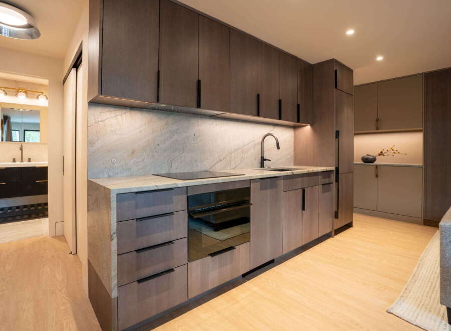 Experience modern living in this sleek kitchen featuring dark wood cabinetry and a stunning marble backsplash.