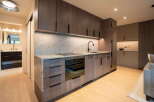 Experience modern living in this sleek kitchen featuring dark wood cabinetry and a stunning marble backsplash.