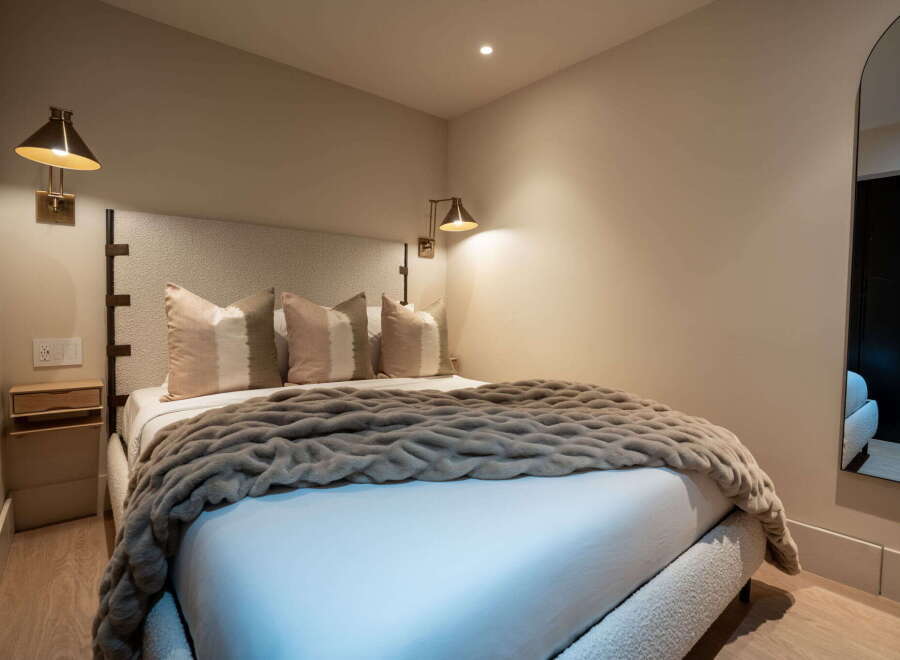 Experience ultimate comfort in this beautifully appointed bedroom, featuring a plush bed adorned with a cozy, textured throw and decorative pillows.