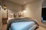 Experience ultimate comfort in this beautifully appointed bedroom, featuring a plush bed adorned with a cozy, textured throw and decorative pillows.