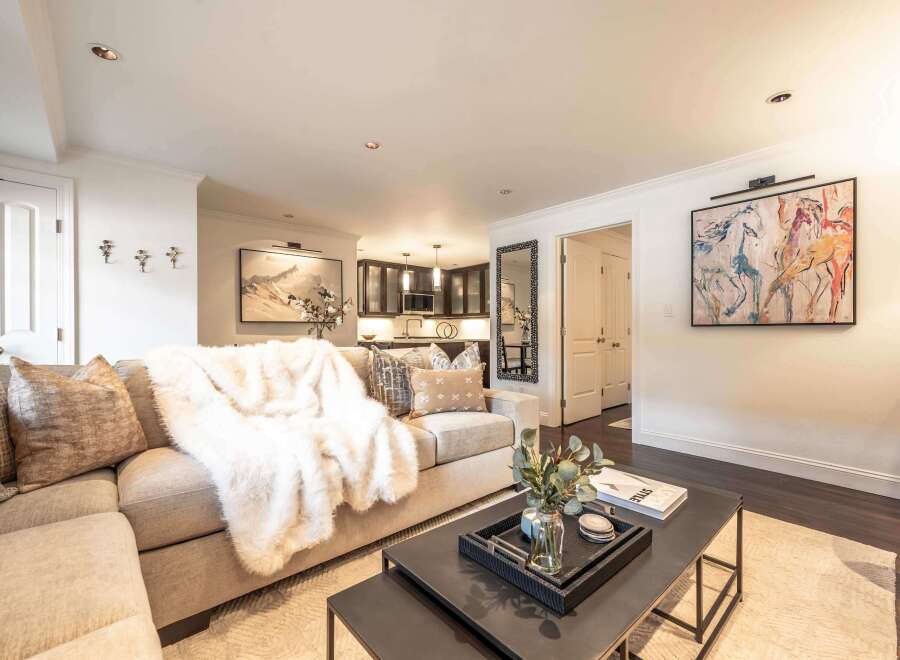 Experience modern living in this beautifully appointed living space, featuring a plush sectional sofa draped with a luxurious faux fur throw.