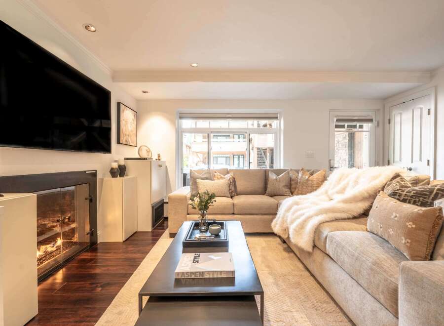 Experience cozy living in this beautifully appointed living room, featuring a modern fireplace with glass doors and a large, flat-screen TV mounted above.