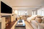 Experience cozy living in this beautifully appointed living room, featuring a modern fireplace with glass doors and a large, flat-screen TV mounted above.