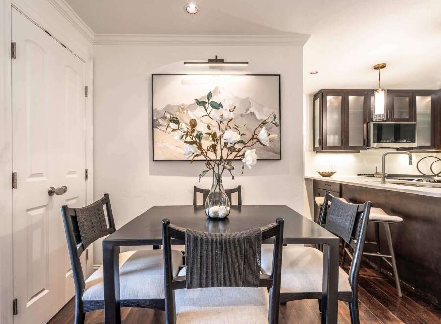 This elegant dining area features a dark wood table set with four chairs upholstered in neutral fabric and accented with woven backs.