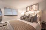 Experience luxurious comfort in this beautifully appointed bedroom, featuring a king-size bed with plush pillows and a textured throw.