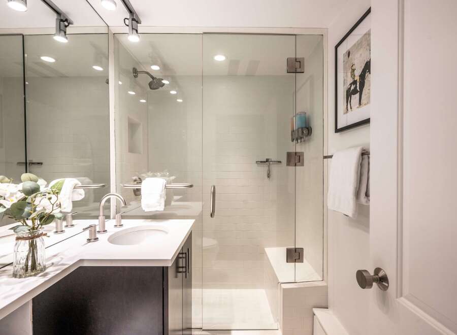 This modern bathroom features a spacious glass-enclosed shower with white subway tile and a built-in bench.