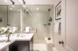 This modern bathroom features a spacious glass-enclosed shower with white subway tile and a built-in bench.