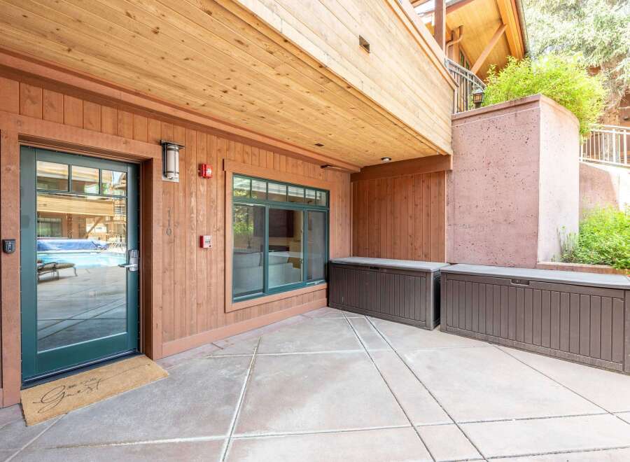 Step outside to your private patio, featuring a welcoming 'Be Our Guest' doormat and convenient storage solutions.
