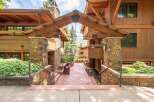 Experience the charm of this mountain-style property, featuring a grand entrance with a covered walkway supported by stone pillars and exposed wooden beams.