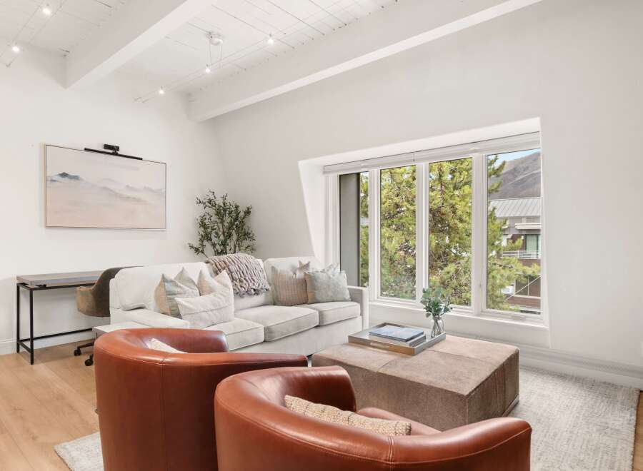 Experience modern living in this bright and airy living room, featuring a comfortable sectional sofa adorned with plush pillows and a cozy knit throw.