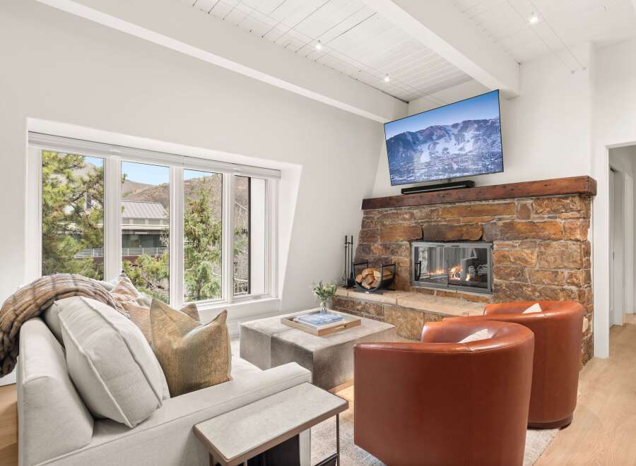 Cozy up by the stone fireplace in this inviting living room, featuring a large flat-screen TV mounted above for entertainment.