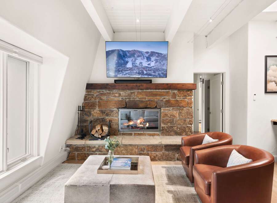 Cozy up by the stone fireplace in this inviting living room, featuring a large flat-screen TV mounted above for entertainment.
