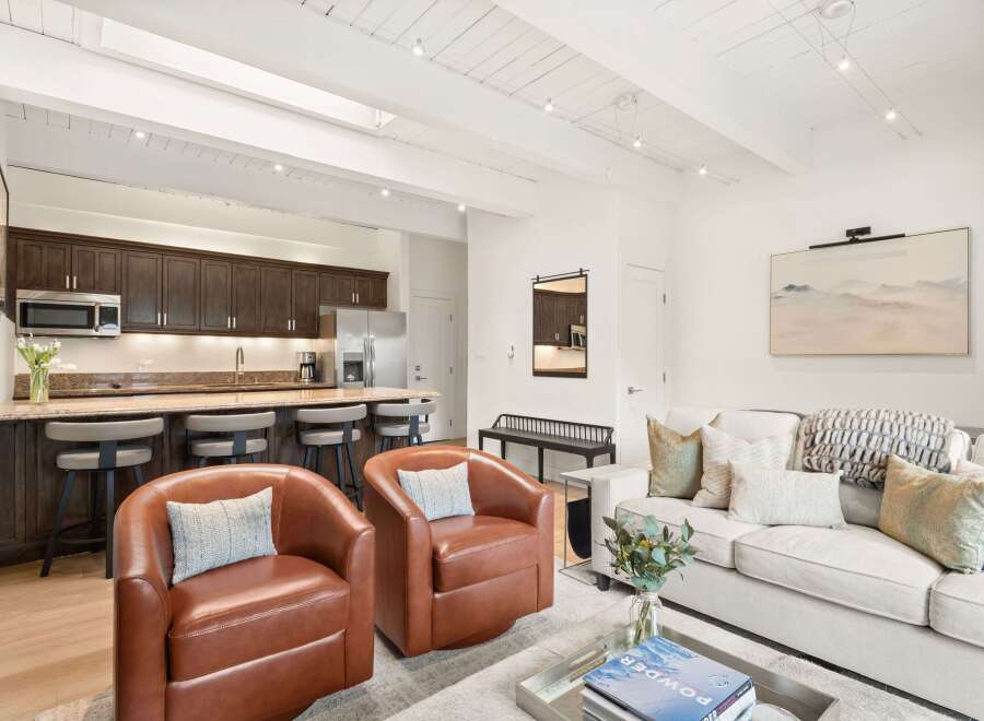 Experience modern living in this stylish open-concept space, featuring a sleek kitchen with dark wood cabinetry and granite countertops, perfect for entertaining.