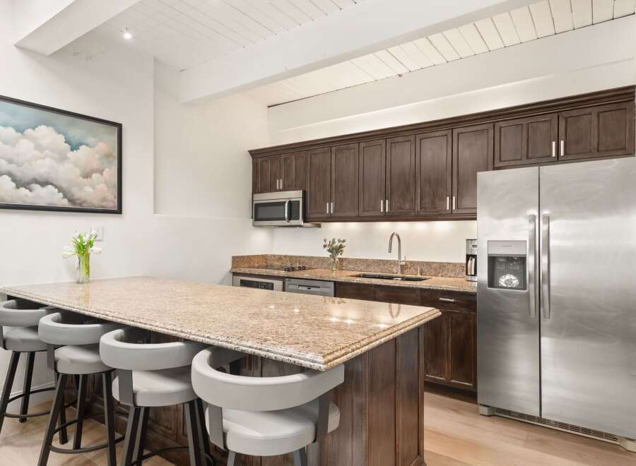 Experience modern living in this beautifully appointed kitchen, featuring rich dark wood cabinetry and a stunning granite-topped island with comfortable seating.