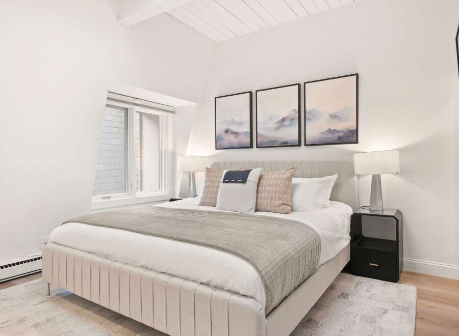 Experience serene mountain views from this beautifully appointed bedroom, featuring a plush king-sized bed and tasteful abstract art.