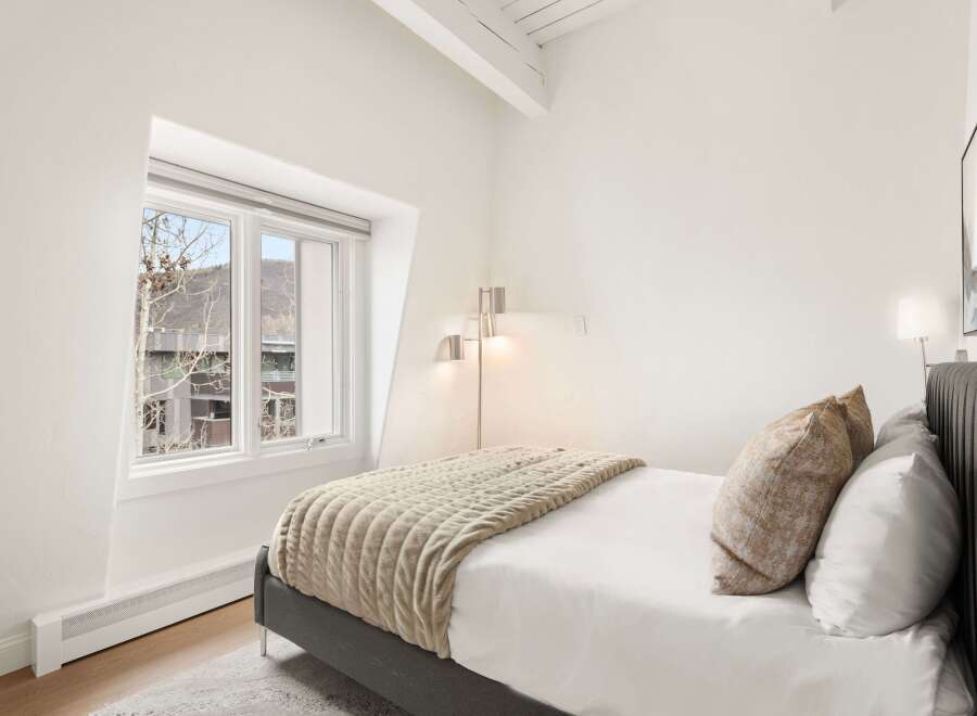 Experience comfort and style in this inviting bedroom, featuring a plush bed adorned with textured pillows and a cozy throw blanket.