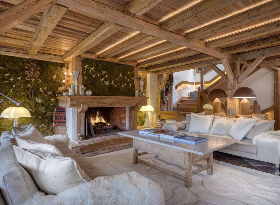 Experience rustic luxury in this stunning living room, featuring exposed wooden beams and a moss-covered accent wall adorned with decorative birds.